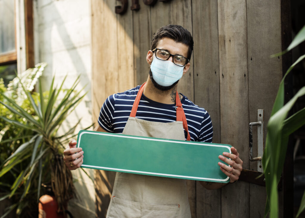 Small business owner holding a blank storefront sign outside a shop